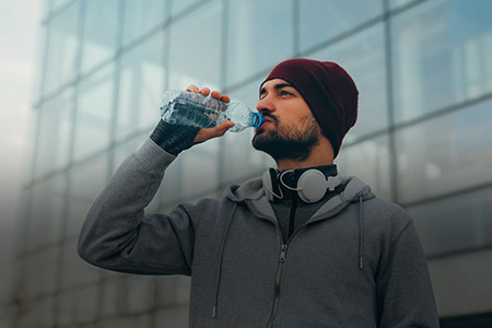 Ao fundo imagem de um homem se hidratando agasalhado