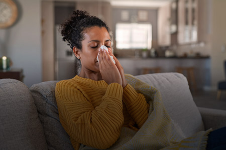Ao fundo imagem de uma mulher resfriada
